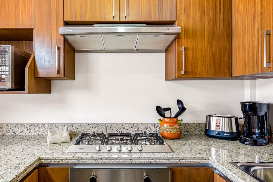Sleek gas stovetop on granite counters with a toaster and coffee maker nearby.