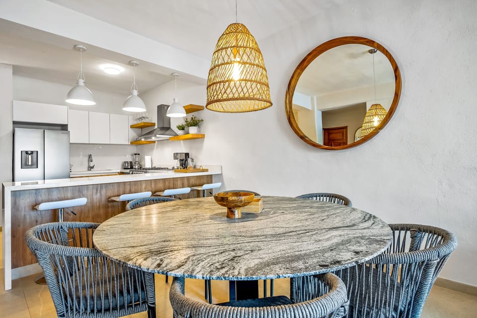 Round marble dining table with woven chairs and a stylish pendant light.