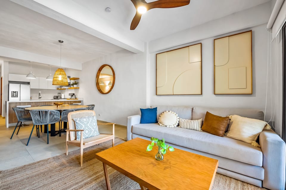 Comfortable sofa setup with a wooden coffee table, armchair, and minimalist wall frames.