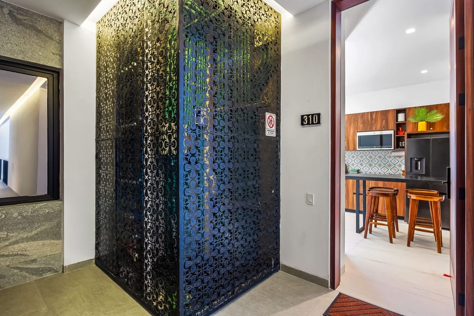 Unit entrance hallway showcasing an intricate black lattice divider next to the open kitchen door.