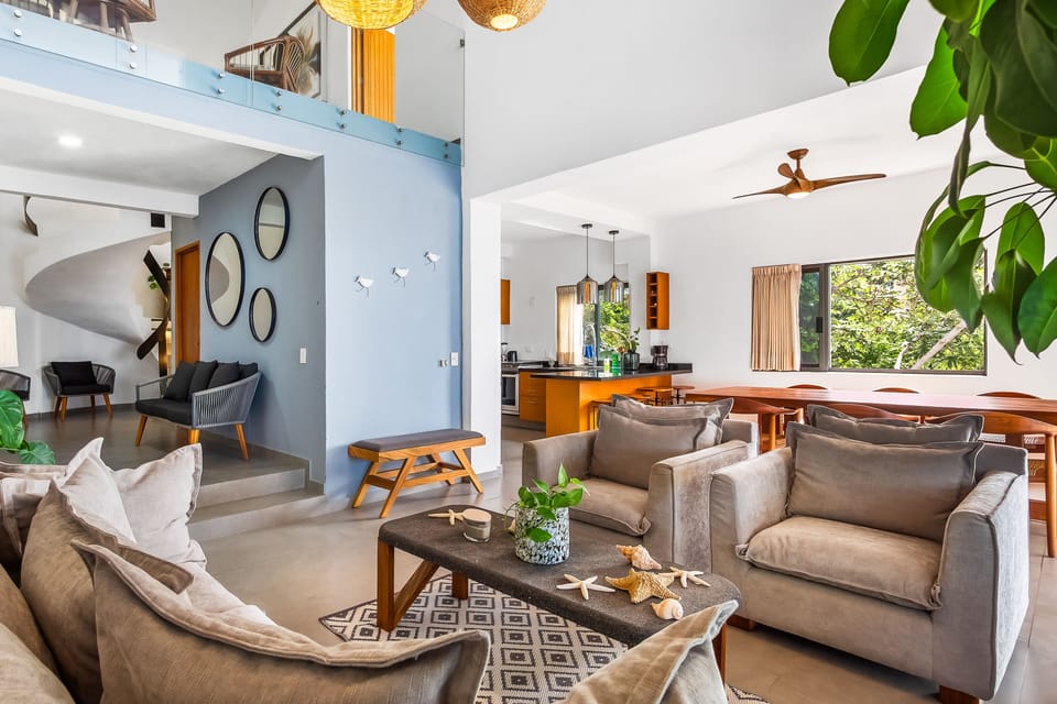 Modern and airy living room decorated with comfortable armchairs, a wooden coffee table, and a view connecting to the dining area.