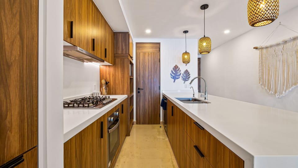 Modern kitchen with rich wood cabinetry, quartz countertops, premium appliances, and everything needed for morning coffee, home-cooked meals, or sunset cocktails.
