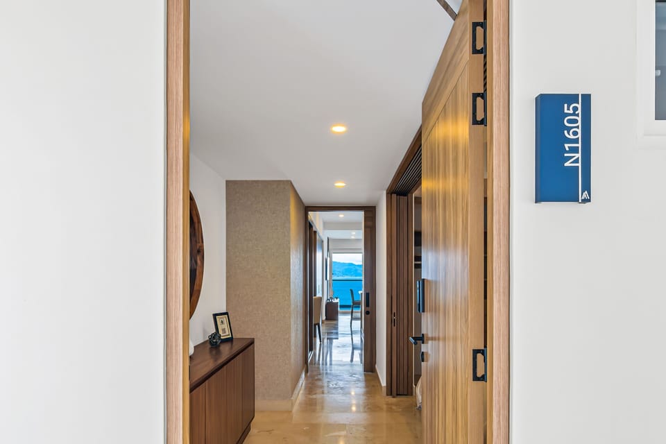Looking from the exterior entryway through the front door down a long, bright interior hallway leading towards the sea.