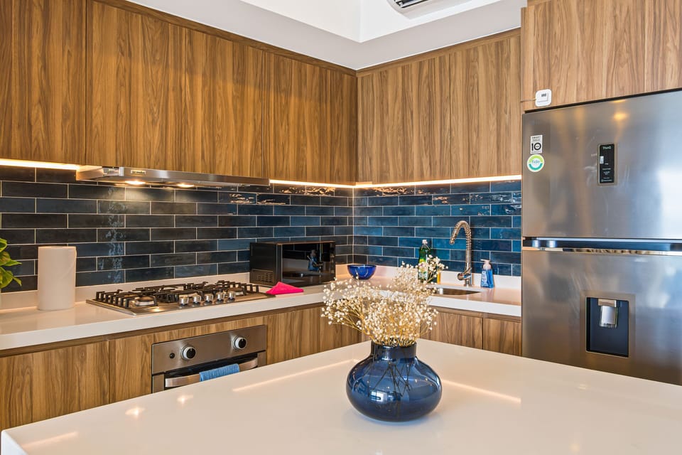 Looking across the white island countertop styled with a blue ceramic vase toward the cooking zone.