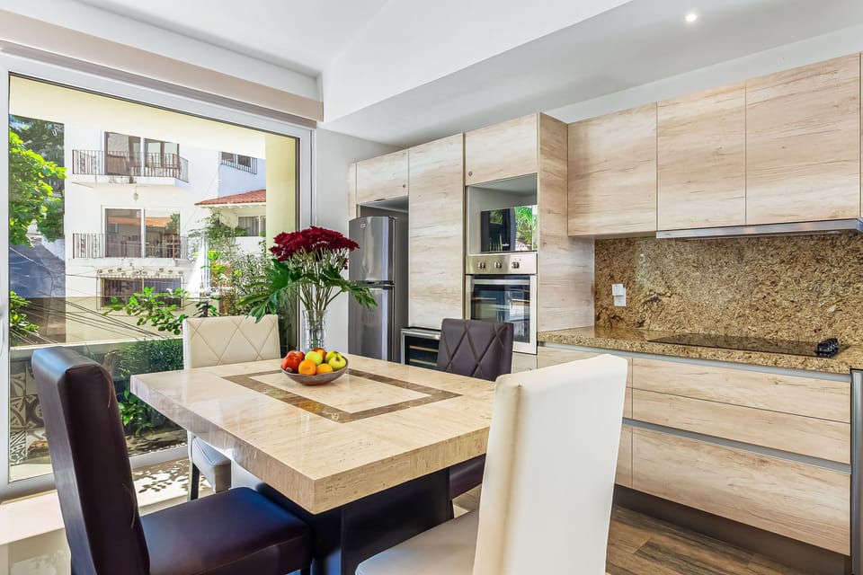 Modern dining table for four seamlessly integrated next to a sleek kitchen with light wood cabinetry.