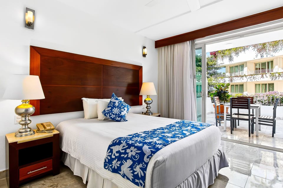 A bedroom featuring a large wooden headboard, blue-and-white patterned accents, lamps, and a sliding glass door opening to a patio.