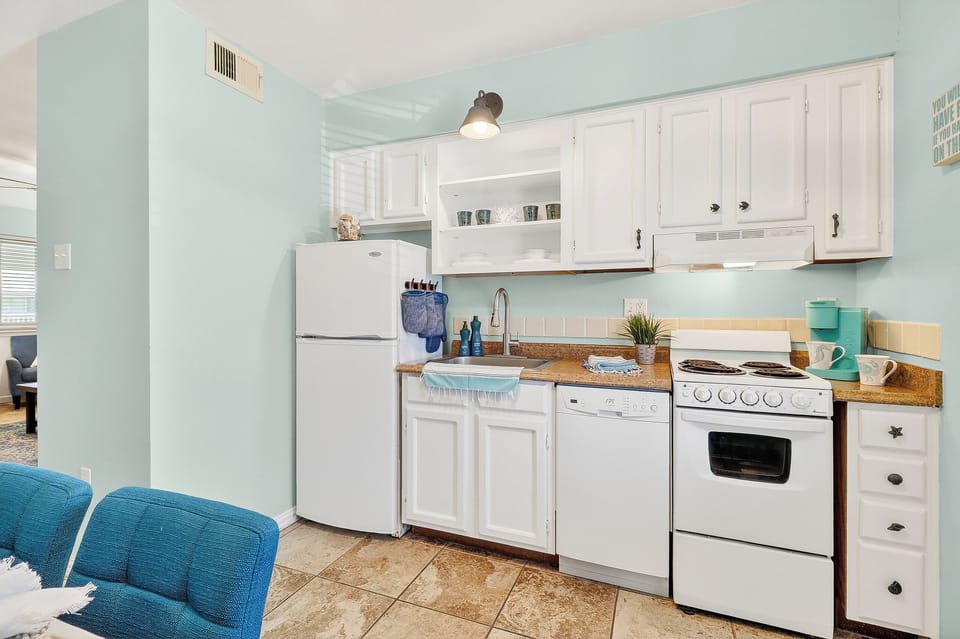 Your coastal-inspired kitchen awaits with charming mint walls, white cabinets, and everything needed to prepare beachside meals.