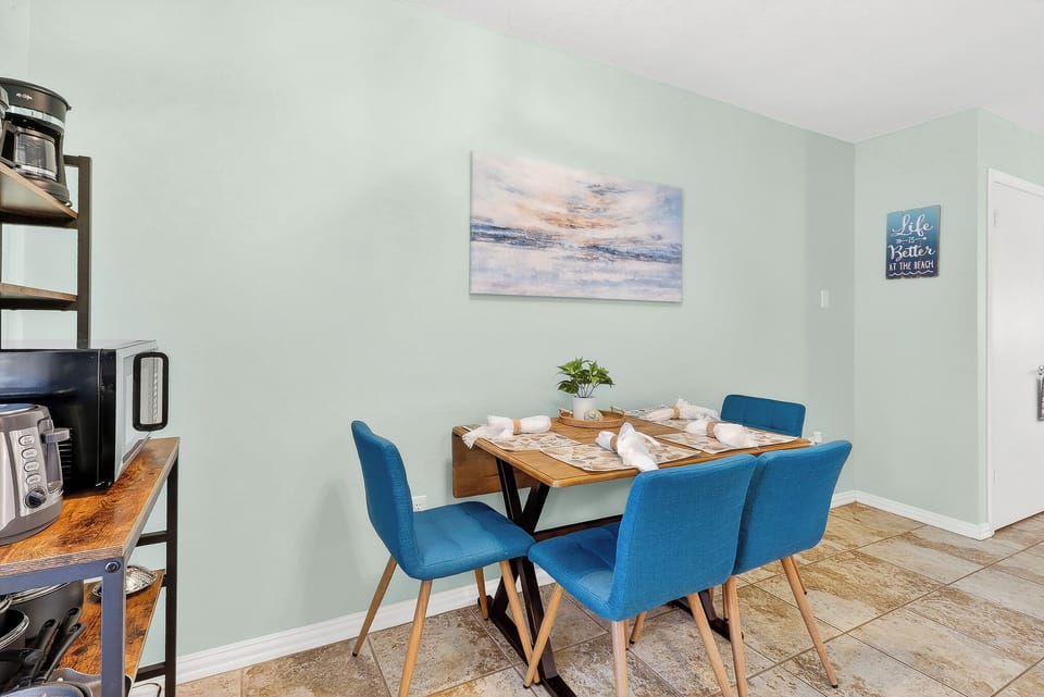 Gather around your stylish dining table with plush blue chairs, where morning coffee and evening meals become special moments in this bright, welcoming space.
