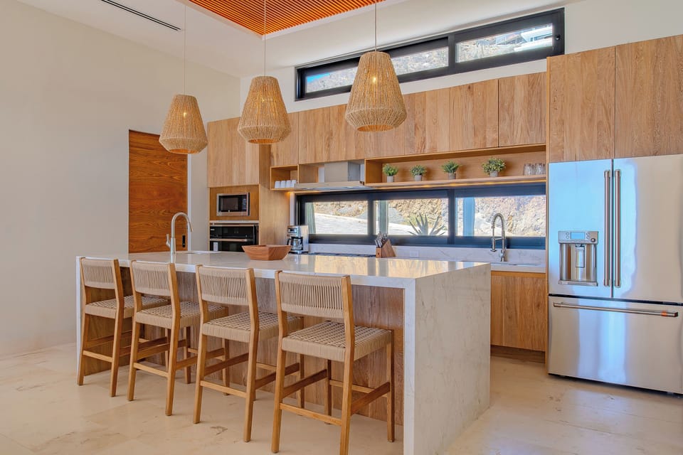 Your modern kitchen awaits with warm wood accents, sleek marble island, and natural light streaming through panoramic windows.