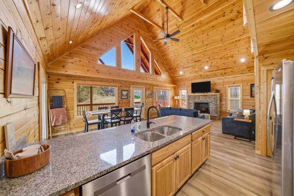 Your open-concept haven blends rustic log charm with modern comfort, where granite countertops meet soaring wood ceilings and cozy fireplace warmth.
