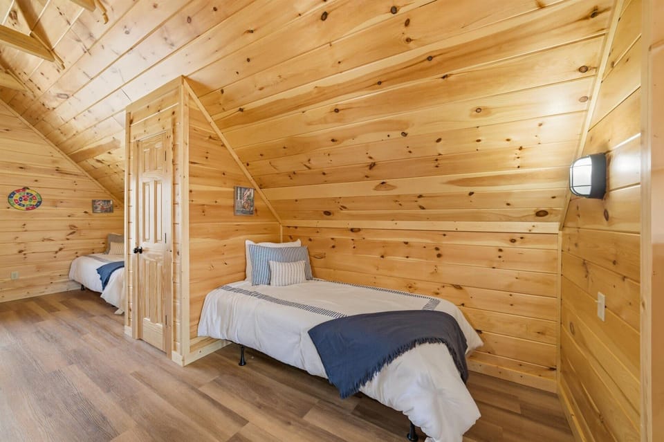 Drift off to sleep in your cozy loft bedroom, where rustic pine walls and beamed ceilings create the perfect mountain retreat atmosphere.
