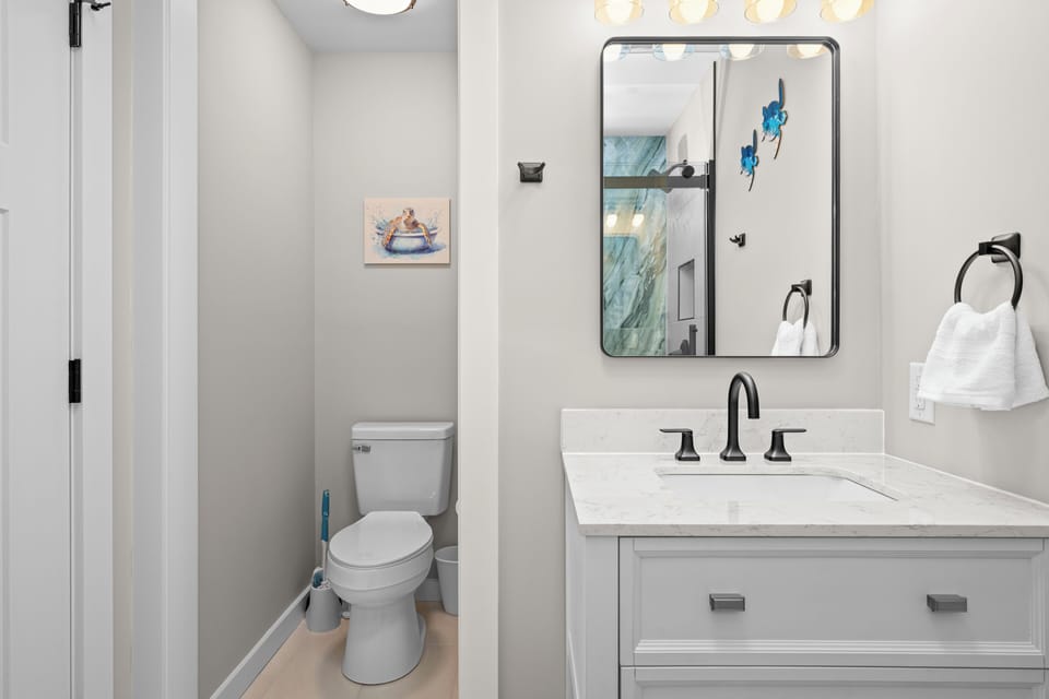 Step into your pristine bathroom featuring elegant marble countertops, modern fixtures, and thoughtful coastal artwork that creates a spa-like retreat for your morning routine.