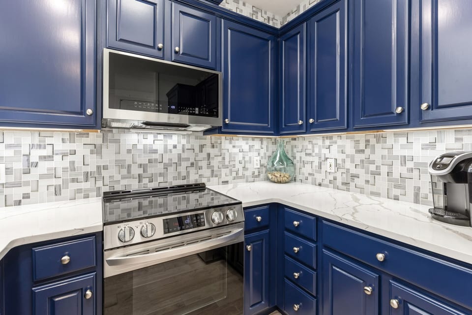 Your stylish kitchen features rich navy cabinets, gleaming marble counters, and modern appliances ready for your culinary adventures.