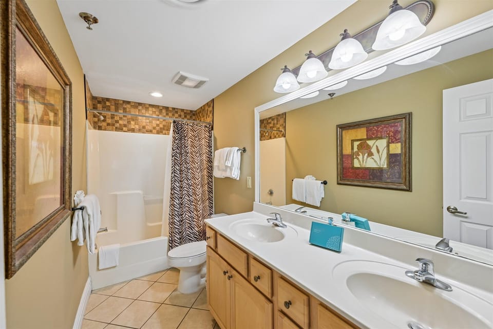 Your spacious bathroom features dual sinks, fresh towels, and a relaxing tub-shower combo with stylish tile accents for your comfort.