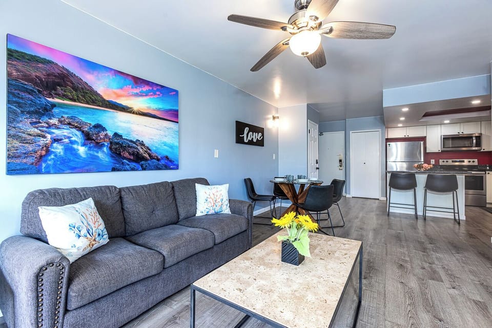 Relax in your bright, modern living space with ocean artwork and cozy seating flowing into the full kitchen.