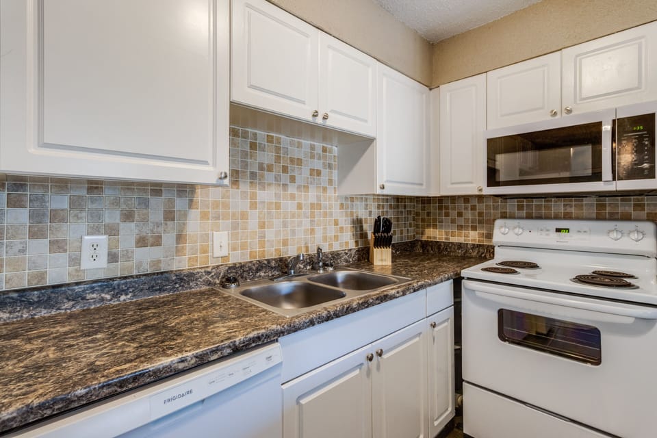 Cook meals in a well-equipped kitchen with modern amenities and chic tile accents.