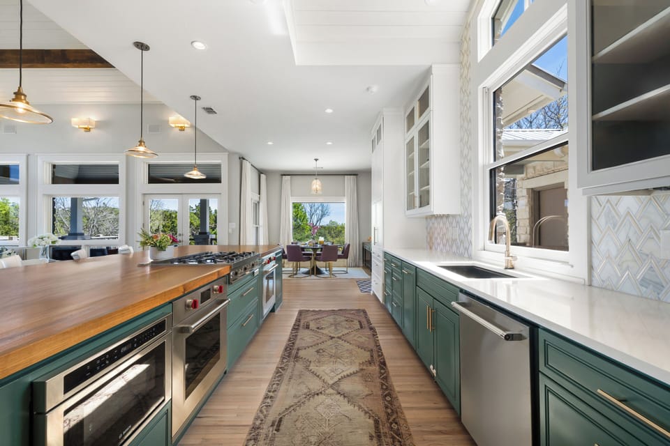 Full kitchen — dual workstations, pro range, breakfast nook  beyond.