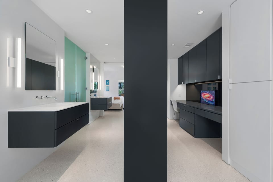 Lower-level suite bath — floating vanity, teal glass partition.