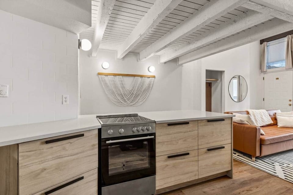 Sleek, modern kitchen with clean-lined cabinetry, quartz countertops, and contemporary appliances. Exposed beams and warm lighting add character, while the open layout flows seamlessly into the living area for easy cooking and entertaining.