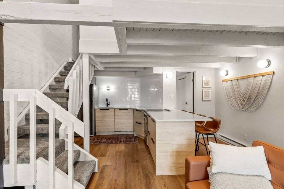 Bright, open kitchen with a spacious island, modern finishes, and warm wood tones. Exposed beams and a seamless connection to the living area create a functional, inviting space ideal for cooking, gathering, and après-ski meals.