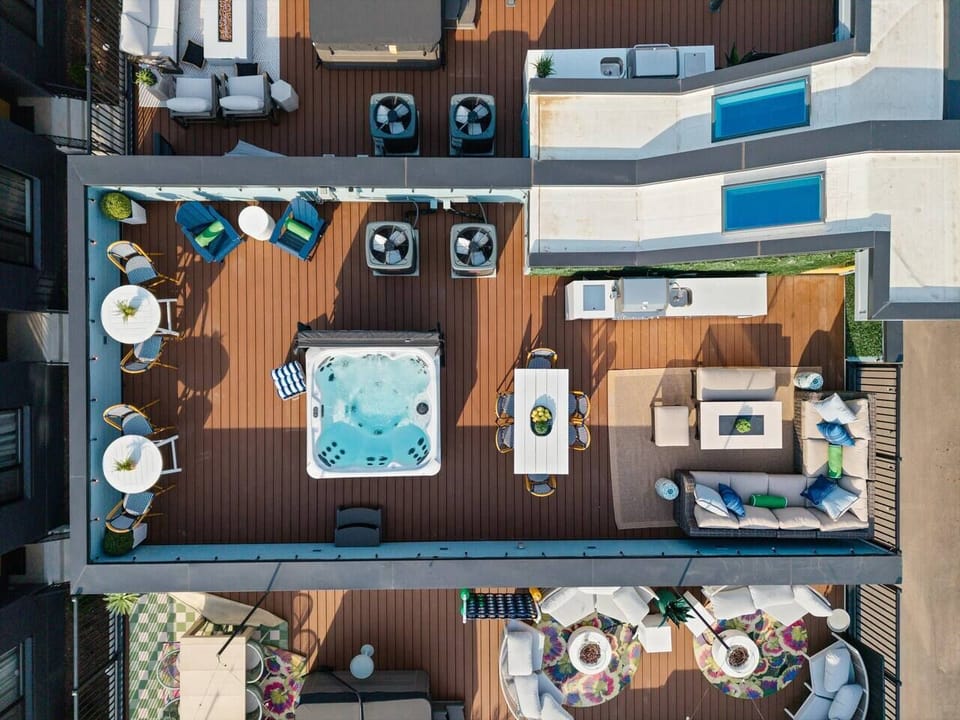 A bird`s-eye view of the outdoor entertainment deck shows the hot tub, lounge area, and pool from above.