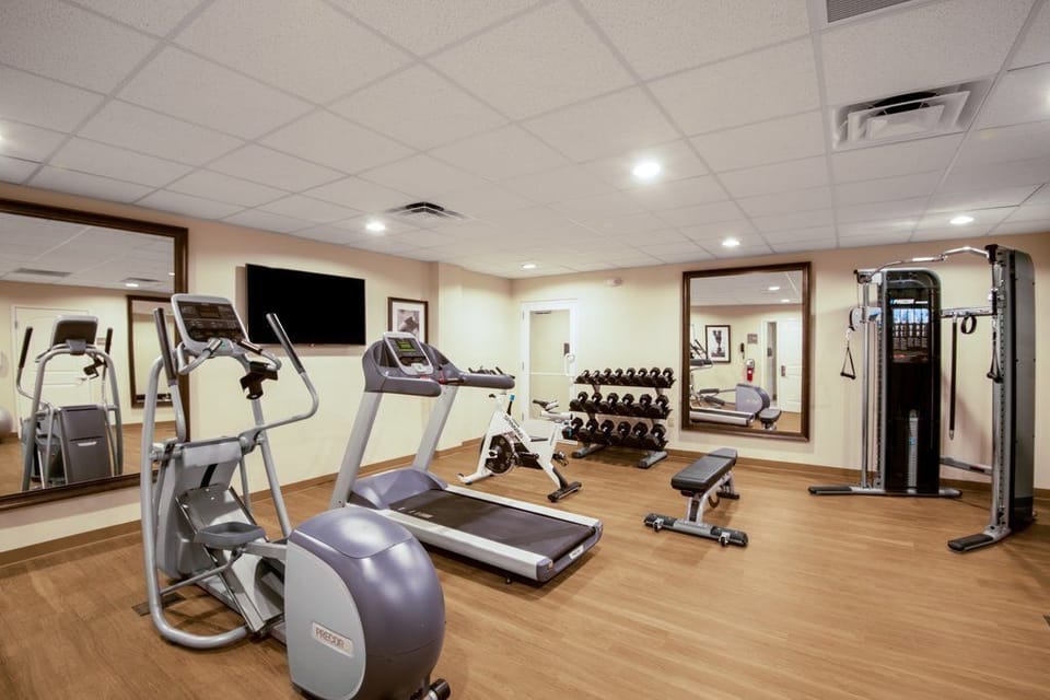 24-hour fitness centre with treadmills, elliptical, multi-station weights, and a full dumbbell rack