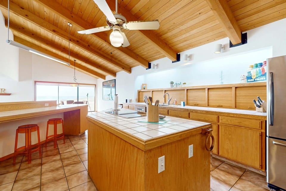 Gather around the island for morning coffee as sunlight streams in, making this kitchen the heart of your seaside retreat.