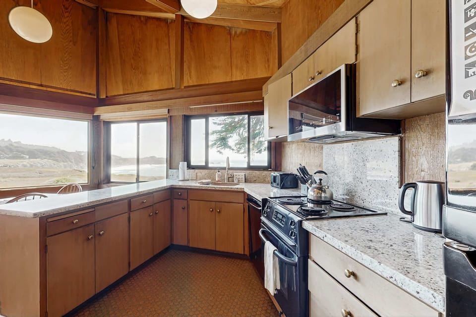 This spacious kitchen invites you to whip up breakfast or dinner, complemented by the soothing backdrop of the sea.