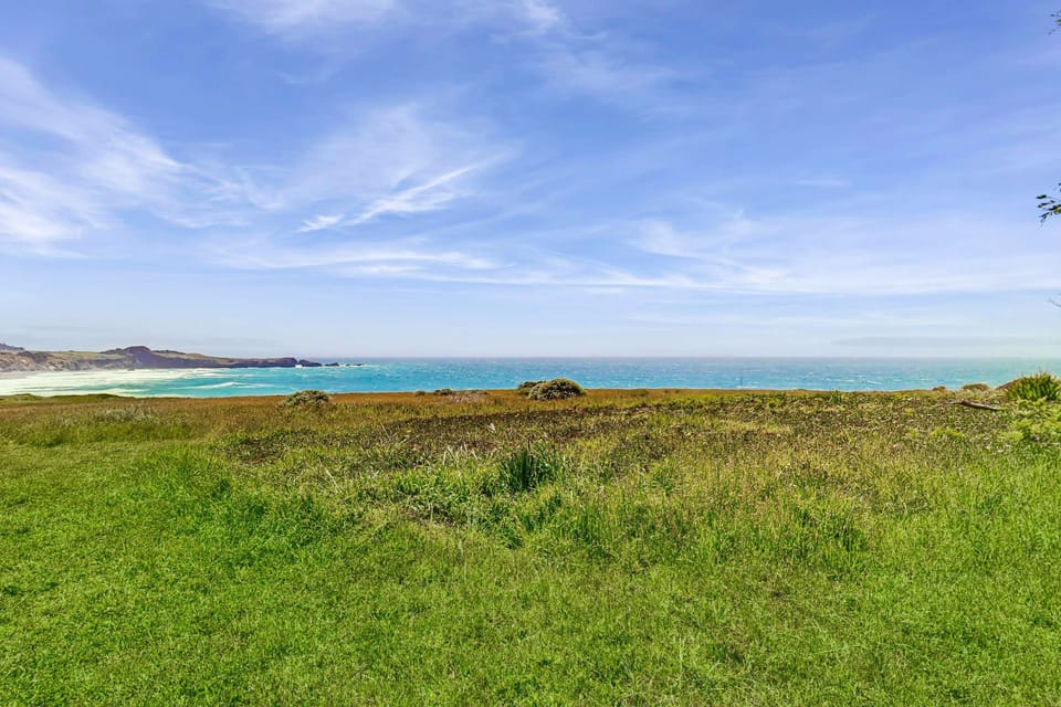 Gaze across the lush green expanse to the sparkling ocean, a tranquil backdrop for your getaway.
