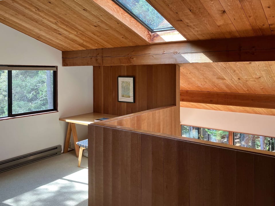 The lofted space offers a perfect nook for productivity or inspiration, bathed in natural light from the skylight above.