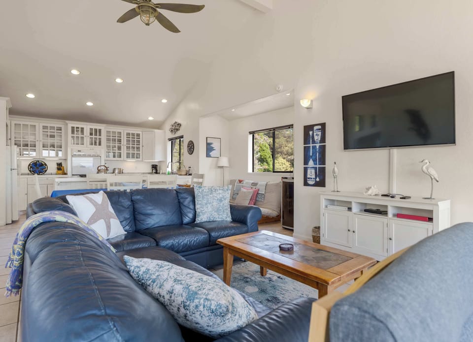 Kick back on the sectional under the vaulted ceiling, with the kitchen, dining table, and a wall-mounted TV all within easy reach.