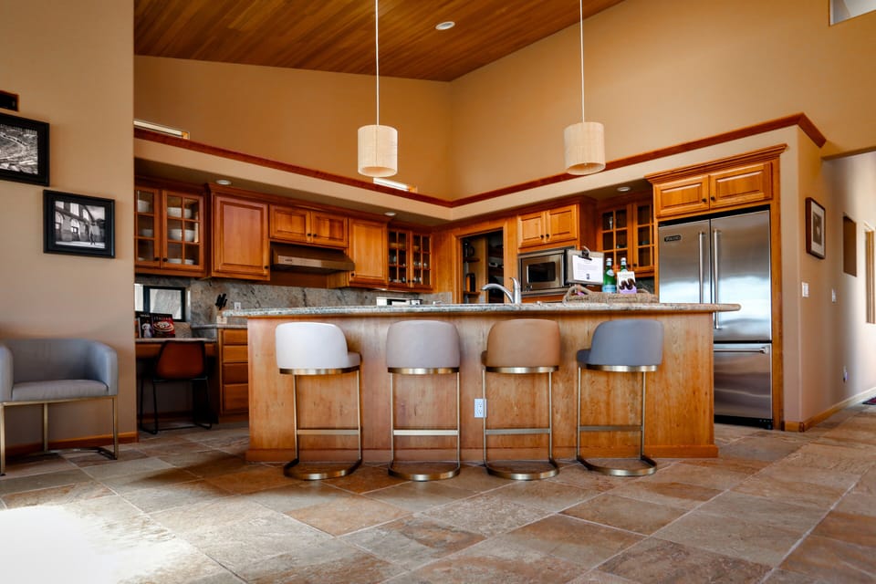 Pull up a bar stool at the granite island — Viking appliances, woven pendants, and room for the whole group to cook together.