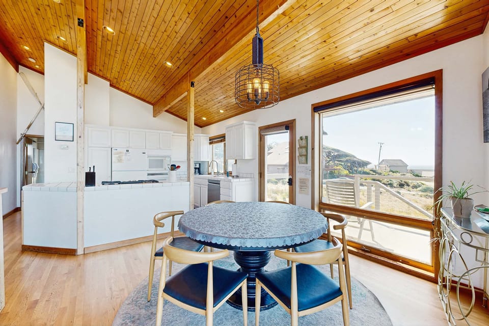 Enjoy laughter and meals at this charming dining area, where large windows frame stunning views of the coastline.