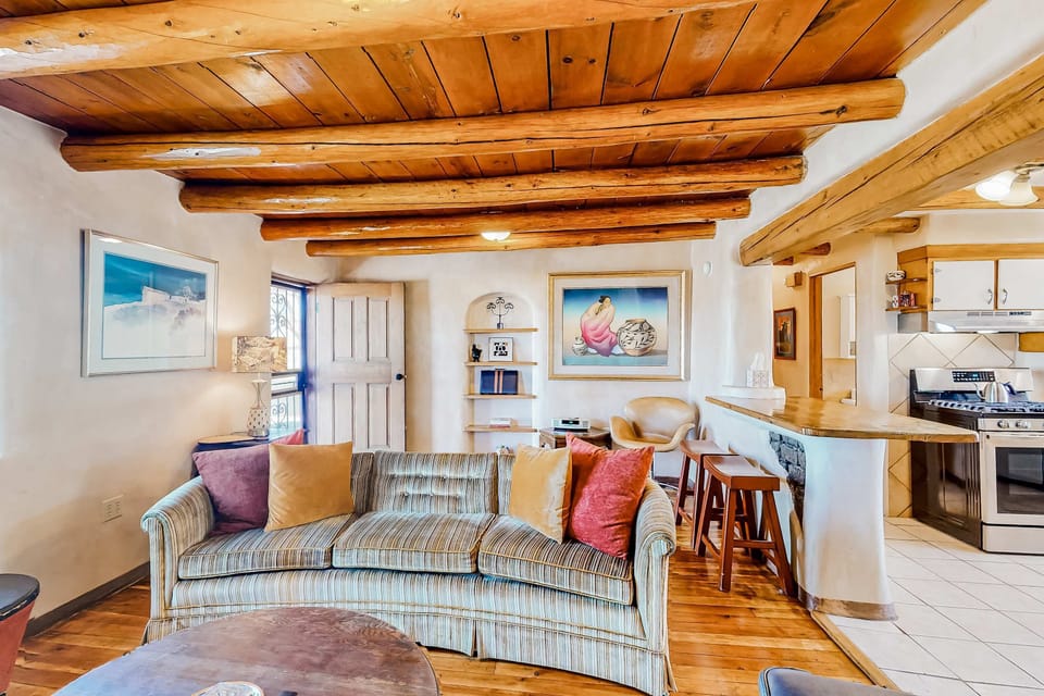 An open living room with viga ceilings and hardwood floors