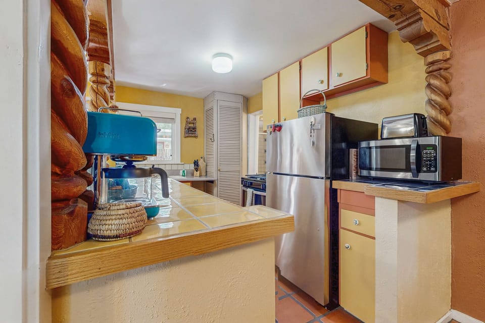 Tile counters and a breakfast bar under carved wood beams
