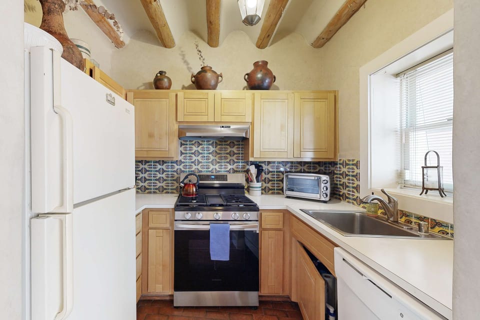 A full kitchen with a gas range and Mexican-tile backsplash