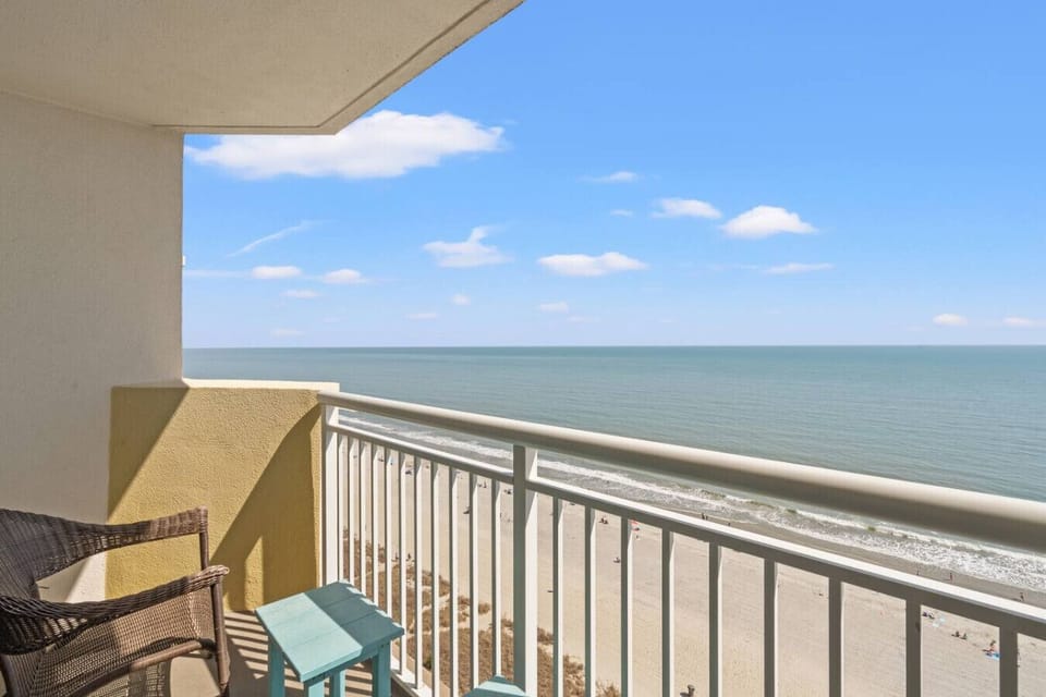 Sweeping oceanfront balcony views stretch across the resort pools, tropical landscaping, and the beautiful coastline below.