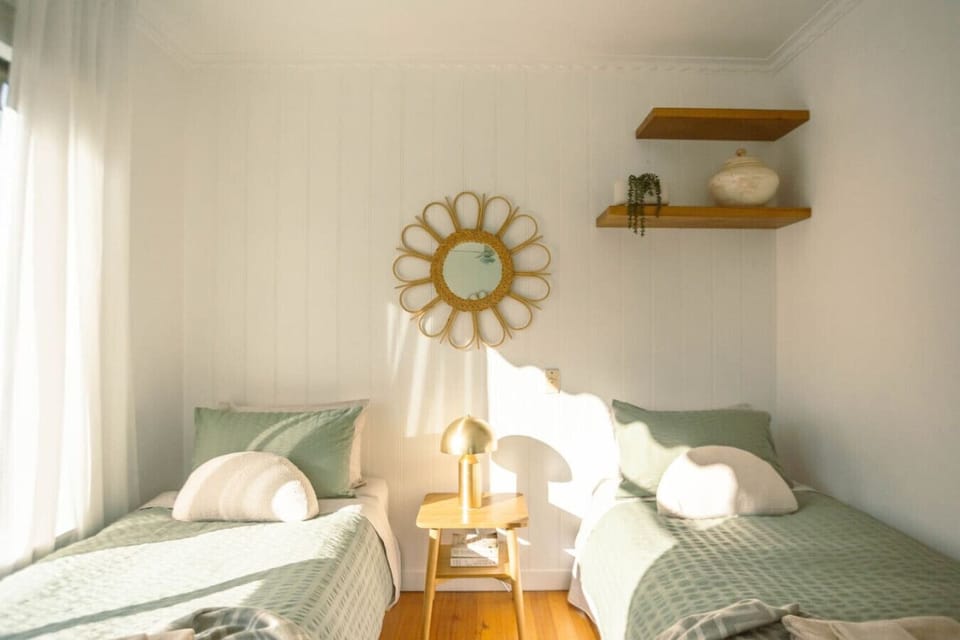 Bedroom 4: Sunlit twin bedroom with sage green beds and sunflower mirror