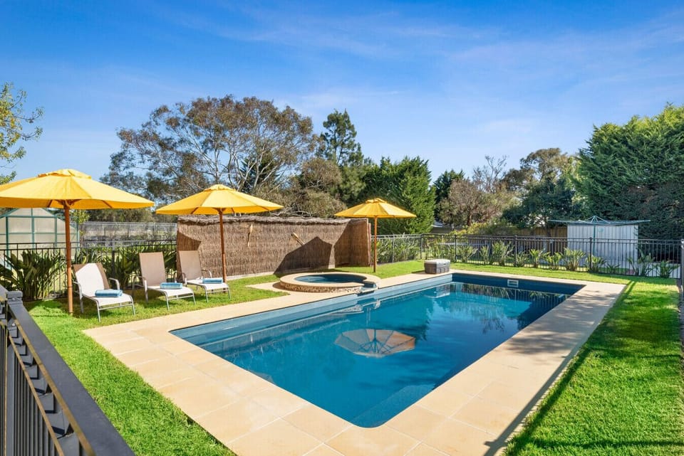 Sparkling pool and spa with sunny yellow umbrellas nearby
