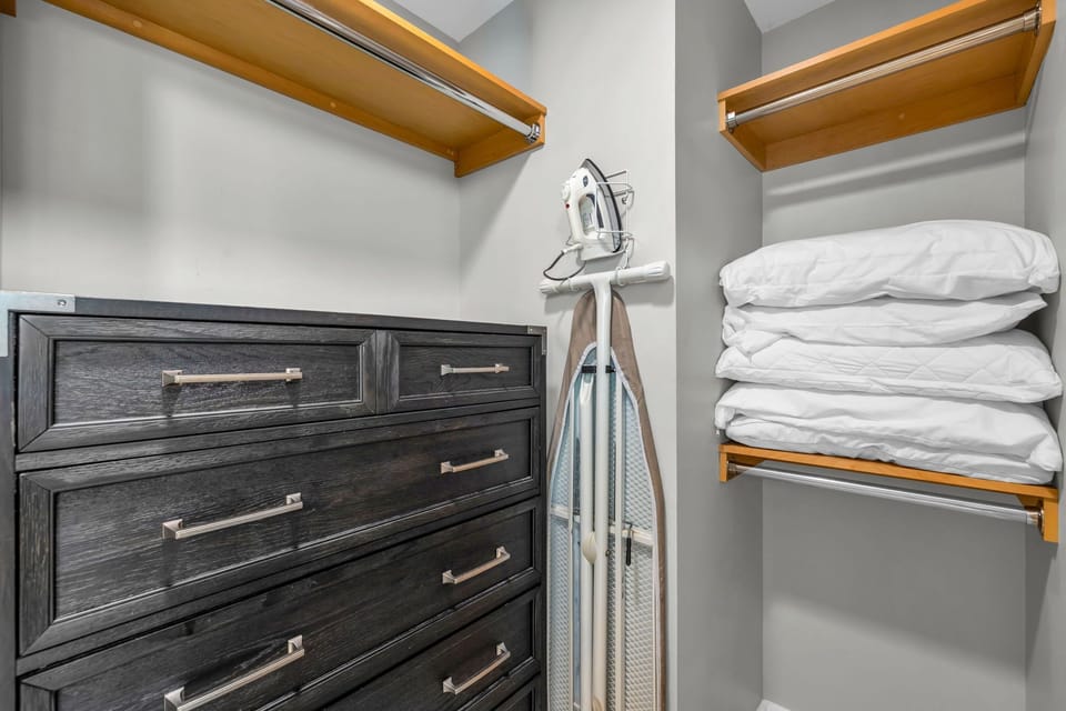 The closet features ample space and an iron and ironing board 