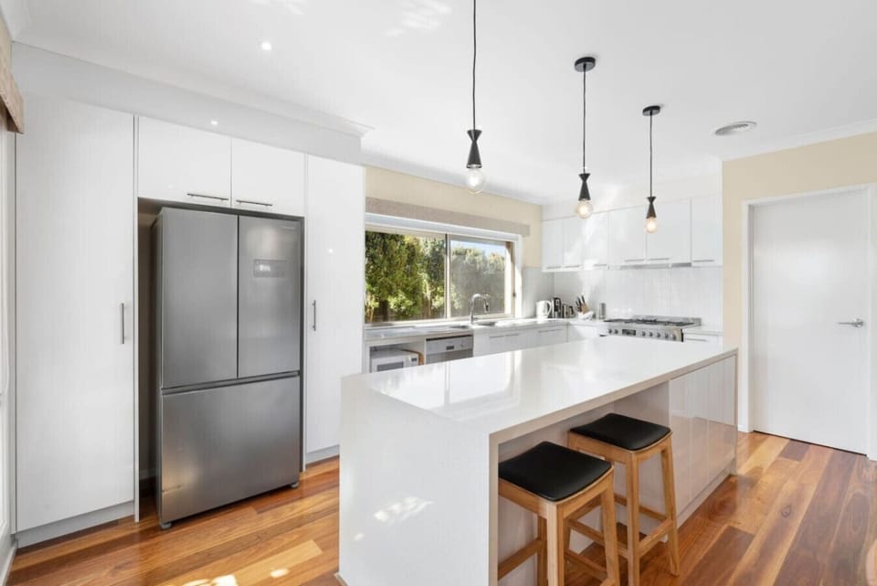 White gloss kitchen, gas range, big island. Whoever cooks wins.