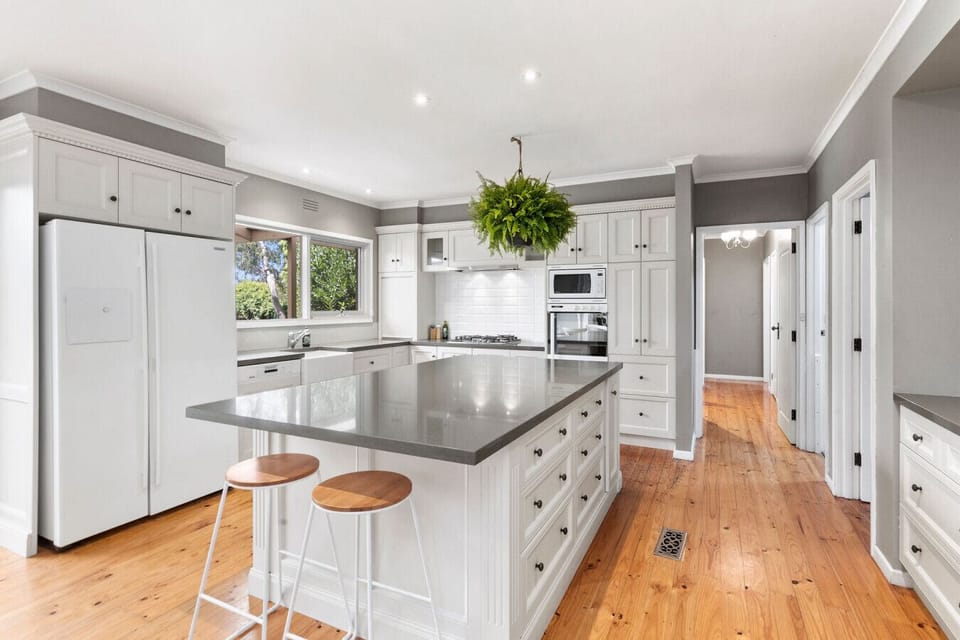 Beautiful white kitchen with island bench and timber floorboards.
