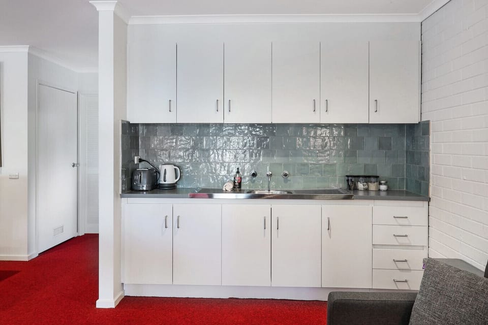 Compact kitchenette with sink, cabinets, and essential appliances