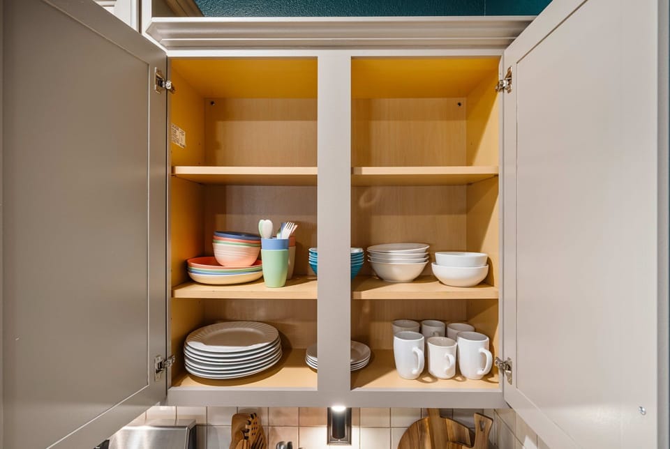 Cabinets stocked with plates, bowls, and mugs