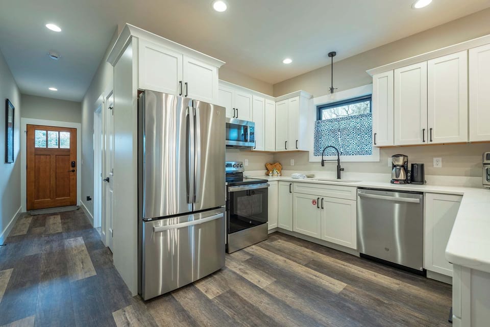 Well-equipped kitchen with stainless steel appliances, dishwasher, kettle, and drip-style coffee maker.