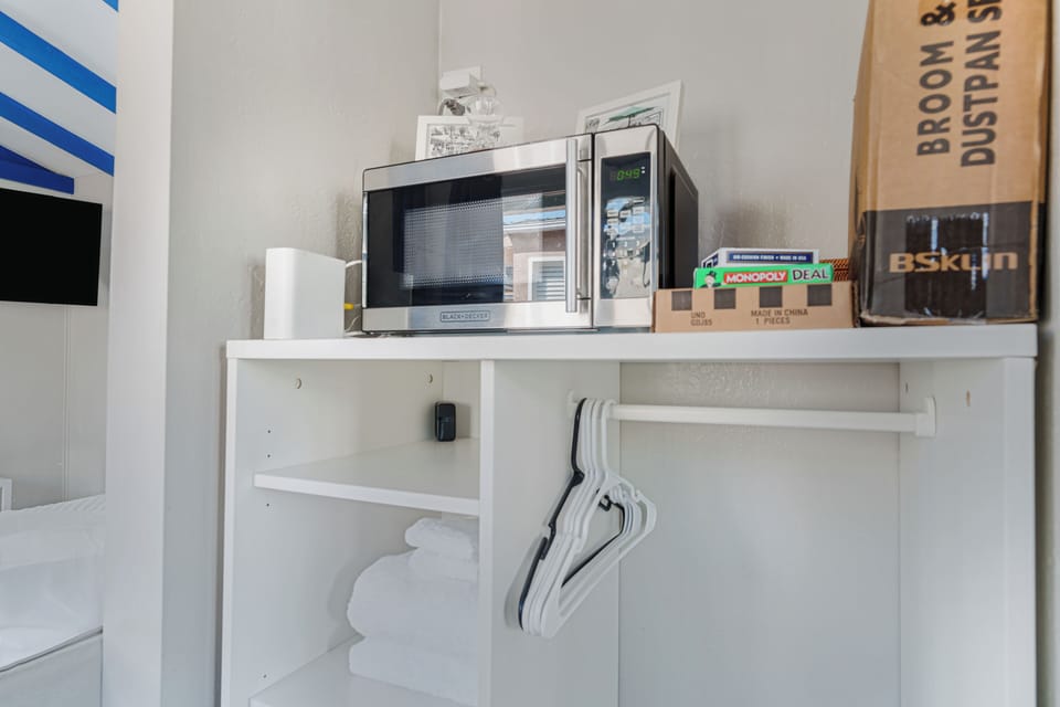 Smart storage solutions include a microwave, hanging space, and fresh linens.