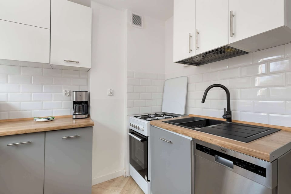 A compact kitchen corner featuring sleek cabinets, a sink, and a cooking area with a stovetop and oven. The neutral color palette and clean lines create a tidy and contemporary look.