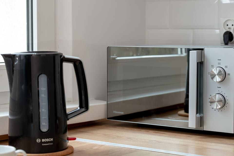 A kitchen countertop with small appliances, including an electric kettle and a compact oven. The setup is practical and designed for convenient everyday use.