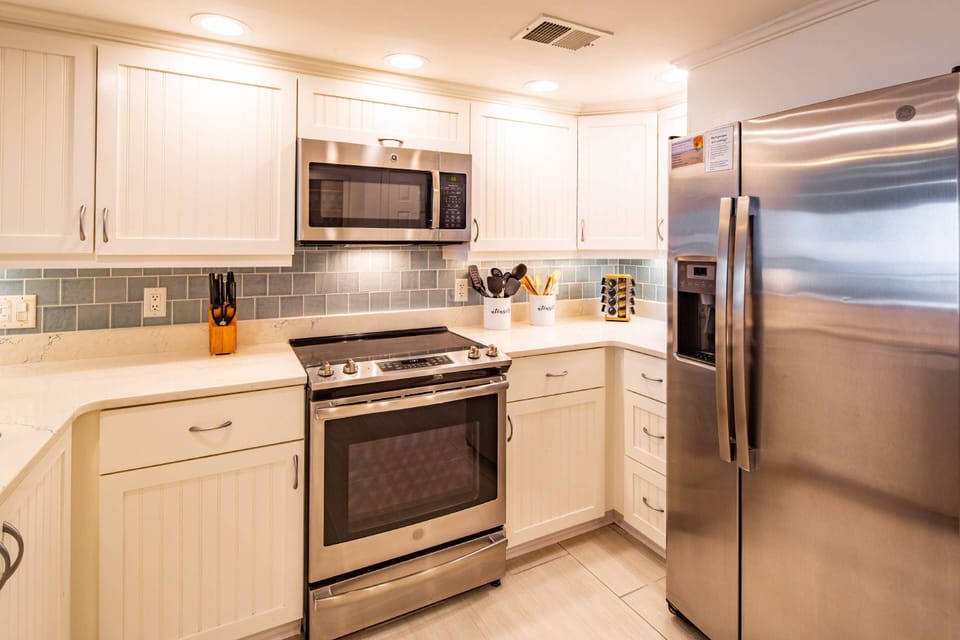 The kitchen features a refrigerator, electric range and microwave.