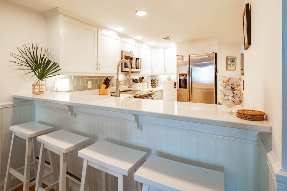 The kitchen features stainless steel appliances, a tiled backsplash and white cabinets.